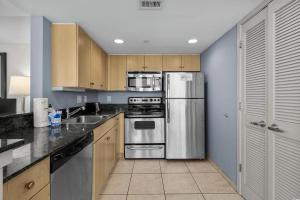 eine Küche mit Küchengeräten aus Edelstahl und Holzschränken in der Unterkunft Glass Wrapped Around Corner Unit Unbeatable View in Myrtle Beach