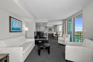 ein Wohnzimmer mit einem weißen Sofa und einem Fernseher in der Unterkunft Glass Wrapped Around Corner Unit Unbeatable View in Myrtle Beach