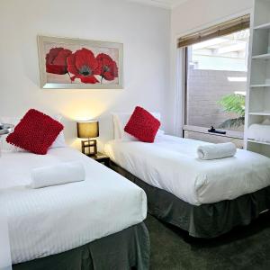 2 camas en una habitación con almohadas rojas. en Garden Retreat on Orr, en Shepparton