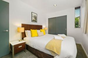 a bedroom with a large bed with yellow pillows at The Alps Apartment in Queenstown