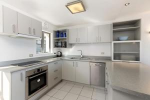 a white kitchen with white cabinets and a sink at Ballarat Bungalow in Queenstown