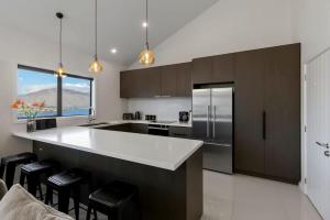 a kitchen with a large white counter and black cabinets at Bluewater Views in Queenstown