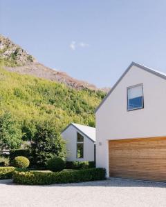 a white house with a wooden garage at Glebe Arrowtown in Arrowtown