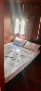 a bed with white sheets and pillows in a room at GIẤY BẢN KÍNH THÀNH - Homestay! in Cao Bằng