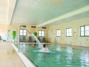 a child playing in a swimming pool in a building at Komfortables ebenerdiges Chalet im Vital Camp Bayerbach in Bayerbach