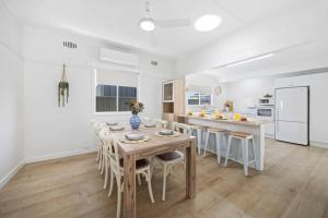 eine weiße Küche mit einem Holztisch und Stühlen in der Unterkunft Nans at Northy - modern river cottage in North Haven