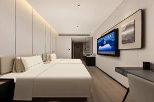 a bedroom with a large white bed and a flat screen tv at Atour Hotel Shanghai Songjiang G60 Dongjing in Shanghai