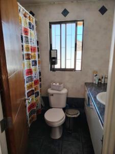 a bathroom with a toilet and a sink and a window at Mi casa es tu casa in La Serena