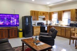 Harbour Place Suites في بلاسينسيا فيليدج: مطبخ بدولاب خشبي وتلفزيون وطاولة