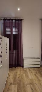 ein leeres Zimmer mit lila Vorhängen und einer Kommode in der Unterkunft Casa Giulia in Triest + 10 Fotos