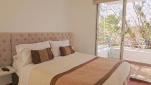 Un dormitorio con una cama grande con una ventana grande. en Norus Providencia, en Santiago