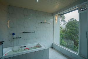 a bathroom with a tub and a large window at Lavee Villa Ella in Ella