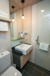 a bathroom with a toilet, sink, and mirror at Champion Hotel City in Singapore