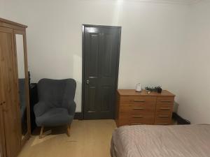 um quarto com uma cadeira, uma cómoda e uma cama em The Gables em Sandwich