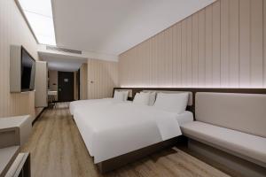 a bedroom with a large white bed and a television at Hanting Hotel Chongqing Lianglukou Caiyuanba in Chongqing