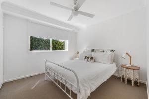 a white bedroom with a bed and a window at Spades - at Lighthouse Beach in Port Macquarie