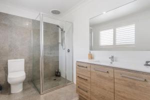 a bathroom with a shower and a toilet and a sink at Spades - at Lighthouse Beach in Port Macquarie