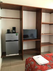 a room with a bed and a tv and shelves at Casa Penélope in Puerto Ángel