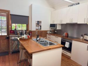 a kitchen with white cabinets and a wooden counter top at Gladstone House in Beechworth