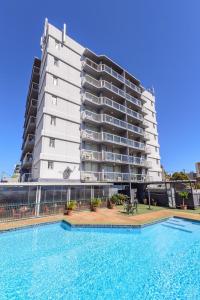 a large building with a swimming pool in front of a building at Highpoint International Hotel in Gladstone