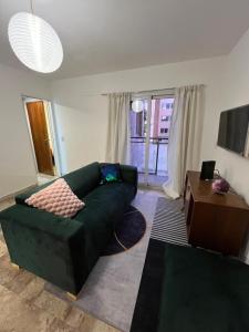 Departamento ideal encantador en morón centro في مورون: غرفة معيشة مع أريكة خضراء وطاولة
