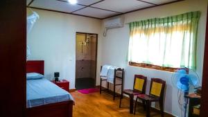een slaapkamer met een bed en twee stoelen en een raam bij Nylander Co-operative Society in Mahabage