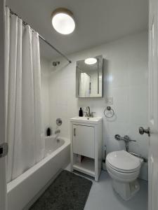 a white bathroom with a toilet and a tub and a sink at Oasis Retreat - Cozy studio in Union Square in New York