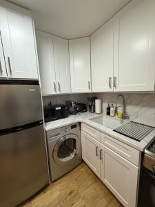 a kitchen with white cabinets and a stainless steel refrigerator at Oasis Retreat - Cozy studio in Union Square in New York