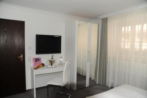 a white room with a desk with a tv on it at Hotel Adler - Weil am Rhein in Weil am Rhein