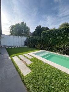 Casa Chalet Ensueños VISTA A LA LAGUNA في شاسكوموس: حديقة خلفية بها مسبح وساحة عشبية