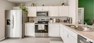 una cucina con mobili bianchi e un frigorifero in acciaio inossidabile di Rainbow Springs Kozy Getaway a Dunnellon Altre 4 foto