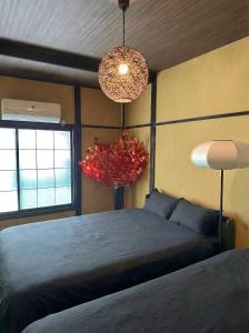 a bedroom with a bed and a vase with a red plant at TRAVELERZ YOKOHAMA Demon Slayer House in Kikuna