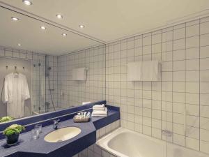 a bathroom with a sink and a bath tub at Mercure Hotel Trier Porta Nigra in Trier +74 photos