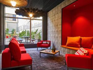 a lobby with red chairs and a table at Ibis Barcelona Plaza Glòries 22@ in Barcelona