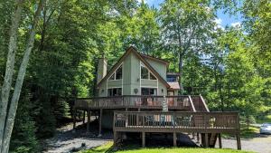 a house with a large deck in the woods at Chalet All Day by AvantStay in Arrowhead Lake