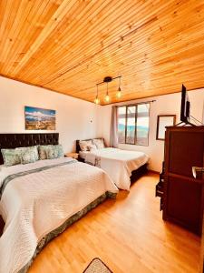 2 camas num quarto com tecto em madeira em Cabaña Valle De La Laguna, jacuzzi y vista al Lago em Aquitania