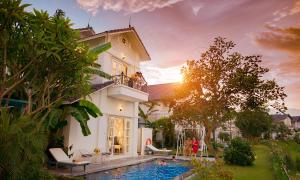 a villa with a swimming pool in front of a house at Vườn Vua Resort & Villas in Ðồng Phú