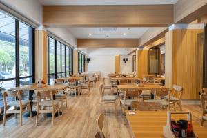 a restaurant with wooden tables and chairs and windows at Kokotel Rayong Beachfront in Ban Pak Khlong Phe