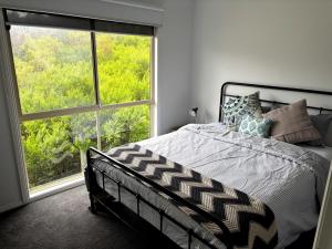 a bedroom with a bed and a large window at Famlee Ties in Venus Bay