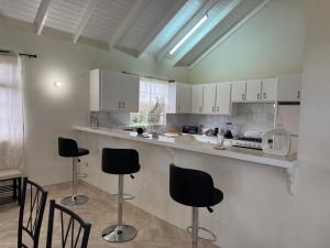 a kitchen with white cabinets and black chairs at Spacious Home 5 Min from Crane Beach Resort in Saint Philip