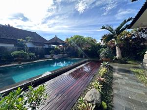 Pondok Naya Ubud في أوبود: مسبح وسطح خشبي في ساحة