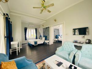a living room with blue furniture and a ceiling fan at Vườn Vua Resort & Villas in Ðồng Phú