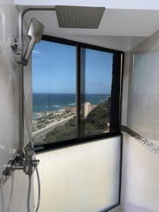 uma janela num quarto com vista para o oceano em Oceanfront Playa Grande 10 min Airport Aeropuerto em Maiquetía