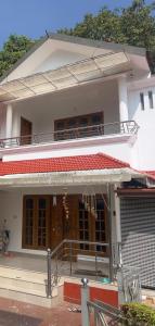 uma pequena casa branca com um alpendre e uma porta em Greenview homestay em Kalpatta