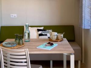 PordicにあるMobil-home confortable pour 2 personnes avec cuisine équipée - API-1-52-1259のボトルと食器が置かれたダイニングテーブル