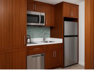 a kitchen with wooden cabinets and a stainless steel refrigerator at Sheraton Kauaʻi Resort Villas- STUDIO in Koloa