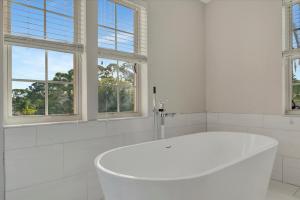 a white bath tub in a white bathroom with windows at 6B Waterfront Game Room Pool Hot Tub Dock in Palm Harbor