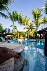 a swimming pool with palm trees in a resort at Beira Rio Palace Hotel in Piracicaba