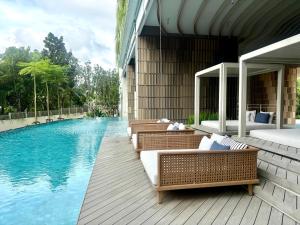 ein Schwimmbecken mit mehreren Korbstühlen neben einem Gebäude in der Unterkunft Vehha Skyline Retreat Condo Corner- Unit 1B & 2B LuxSuite in Hua Hin + 58 Fotos