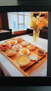 einen Tisch mit Teller mit Lebensmitteln und eine Vase mit Blumen in der Unterkunft Greenland Mansion in Shanghai